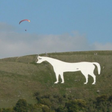 The Westbury White Horse, on the escarpment of Salisbury Plain. It is the oldest of several white horses in Wiltshire. There is no evidence of its existence before 1742. Author Chris Downer, whilst paragliding. Two people are standing on the horse for scale. Creative Commons